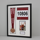 a framed display with a medal, a race number, and a photo of a runner.