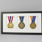 A framed display of three medals, each with a unique design and color, arranged in a row.